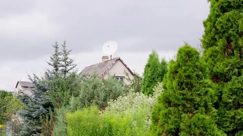 Television satellite dish mounted on chimney above roof of rustic home framed Vídeo Stock 344356749