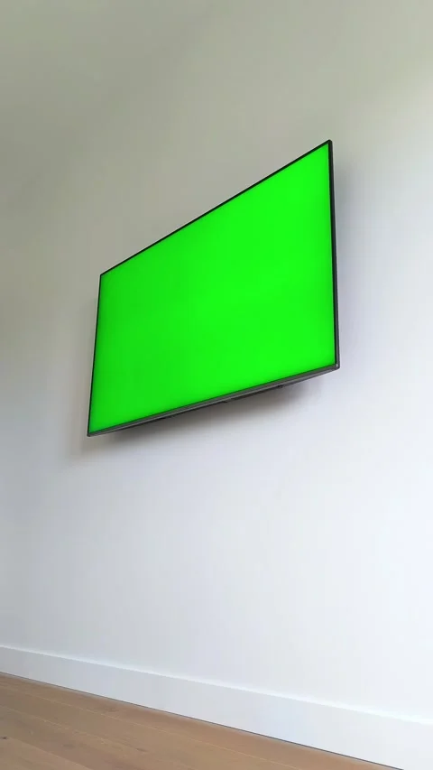 Television screen mounted on a white wall at home lights up turning green f.. Stock Footage 337774219