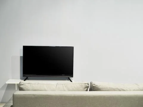A television set with a beige colored sofa Stock Photos