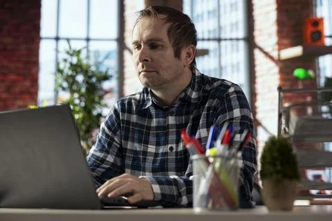 Teleworker in apartment workspace checking emails on laptop Foto stock