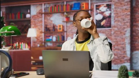 Teleworker drinking coffee while using notebook at home to write emails Stock Photos