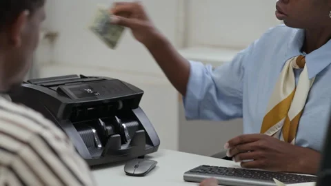 Teller Counting Banknotes in Electronic Device before Giving to Client in Bank Stock Footage 314175535