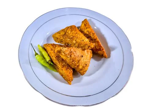 (Tempe mendoan) Triangular fried tempeh wrapped in wheat flour produces a sav Stock Photos