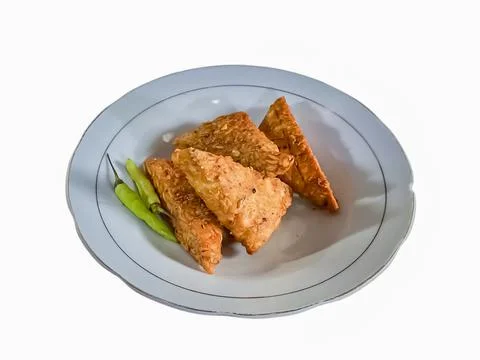 (Tempe mendoan) Triangular fried tempeh wrapped in wheat flour produces a sav Stock Photos