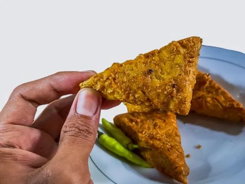 (Tempe mendoan) Triangular fried tempeh wrapped in wheat flour produces a sav Stock Photos
