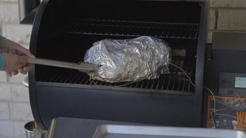 Temperature probe removed from wrapped smoke meat Stock Footage 244689393