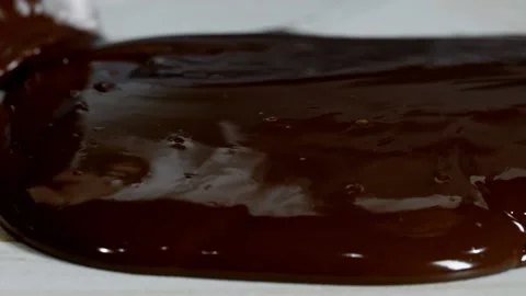 Tempering melted chocolate on natural stone. Woman's hands and spatula close-up. Video stock 148677483