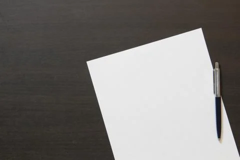 Template of white paper with pen on dark wenge color wooden background. Stock Photos