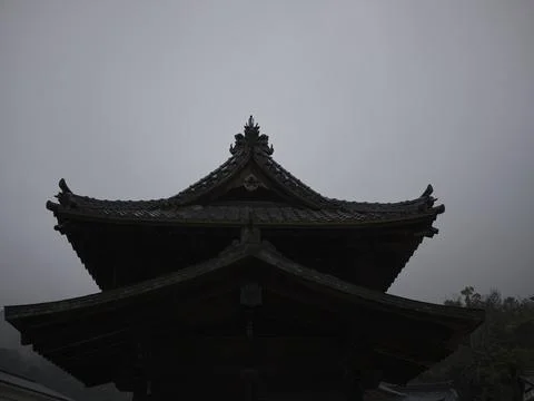 A temple hall and a distant red torii in the mist, Japan Stock Photos