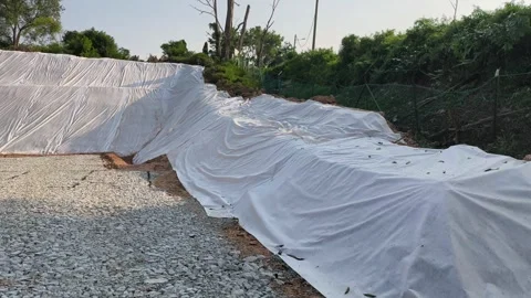 Temporary Plastic Sheeting on Cut Soil Slope for Erosion Control Stock Footage 336646801