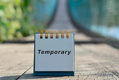 Temporary text written on white note with blurred background of hanging bridg Stock Photos