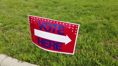 Temporary VOTE HERE sign in grass to guide voters to the polls politics Video stock 107628525