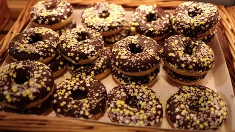 A tempting display of chocolate-glazed donuts decorated with yellow and white st Stock Footage 295673219