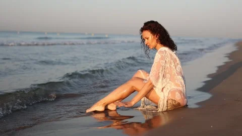 Tempting woman wearing only white thin wet tank top posing on sand on seashore Stock Footage 291663131