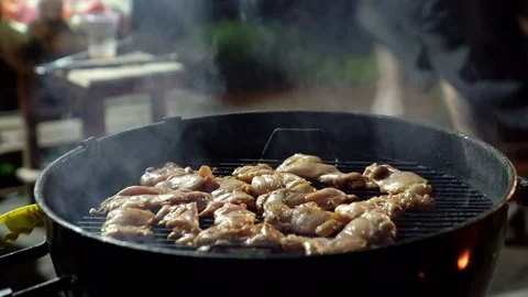 Temptingly spicy chicken wings being grilled over the bright glowing coals of a Stock Footage 92793738
