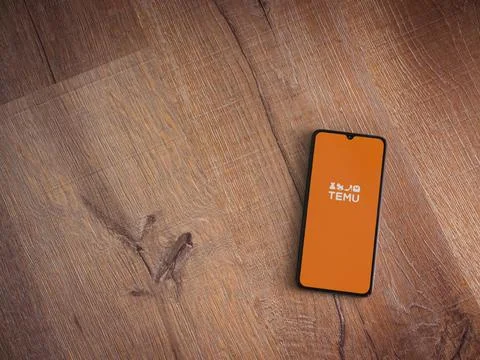 Temu app launch screen on smartphone on wooden background Stock Photos