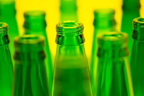Ten Green Empty Beer Bottles Shot with Yellow Light. Stock Photos