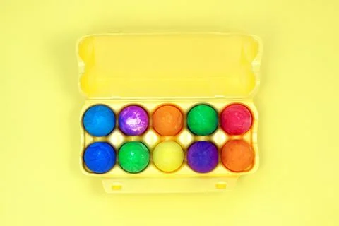 Ten multicolored easter eggs in yellow egg box on yellow background Stock Photos