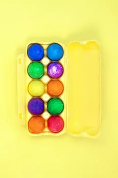 Ten multicolored easter eggs in yellow egg box on yellow background Stock Photos