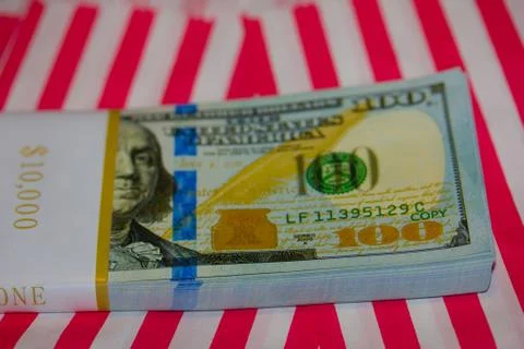 Ten Thousand Dollars Stack in hundreds on Red &amp; White Striped Background Stock Photos