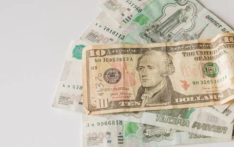 A ten US Dollar bill lying on top of Russian Ruble banknotes on a white backg Stock Photos