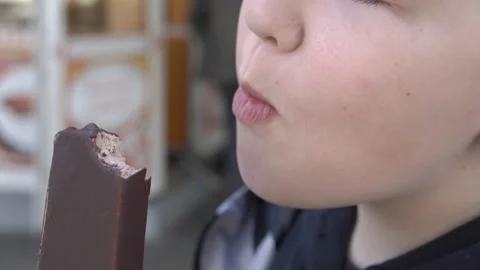 Ten-year-old boy biting into chocolate ice cream close-up Stock-Footage 248363305