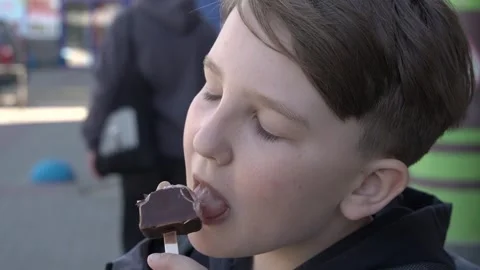 Ten-year-old boy biting into chocolate ice cream close-up Stock-Footage 248956218