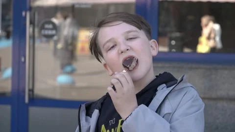 Ten-year-old boy biting into chocolate ice cream close-up Video stock 249045287