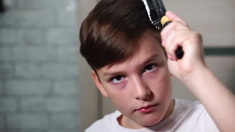 Ten year old boy combing his hair standing in front of a mirror looking at the c Stock Footage 306355590