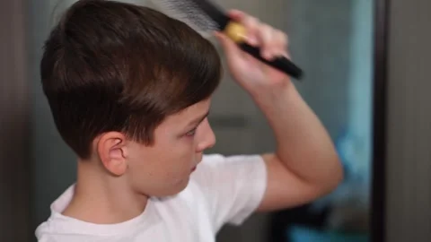 Ten year old boy combing hair standing in front of mirror side view Stock Footage 306355643