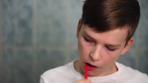 A ten year old boy is concentrating on brushing his teeth with a red toothbrush Video stock 306355181