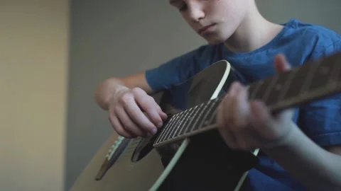 Ten year old boy playing an acoustic guitar 스톡 동영상 87352397