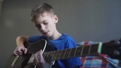 Ten year old boy playing an acoustic guitar Stock Footage 87352416