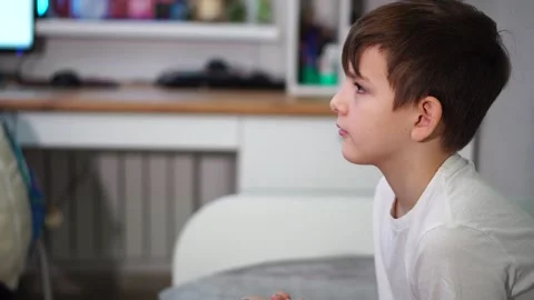 Ten year old boy playing game console sitting on bed Stock-Footage 297553121