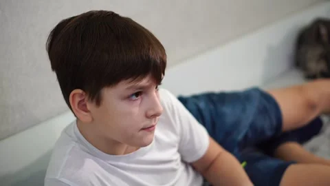 Ten year old boy playing game console reclining on bed Stock Footage 297553170