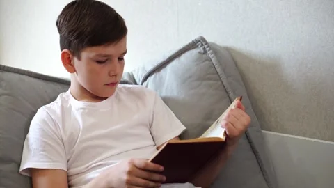 Ten year old boy reading a book lying on his bed in his room Stock Footage 306355311