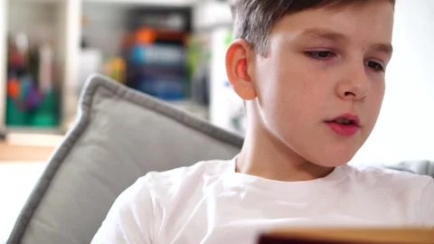 Ten year old boy reading a book lying on his bed in his room Video stock 306355368