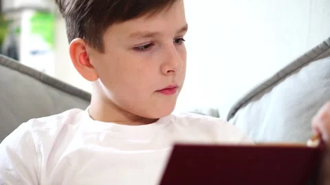 Ten year old boy reading a book lying on his bed in his room Video stock 306355433