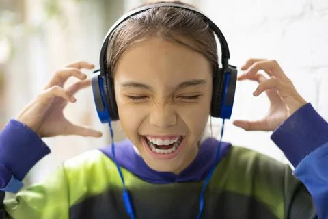 A ten-year-old girl listens to loud music through headphones. She sings along Stock Photos