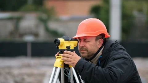 A tenant engineer in  helmet on a construction site using a theodolite marks Stock Footage 165494838