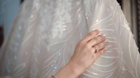Tender bride hand slowly touching her glowing lace wedding dress before wearing Stock Footage 225494914