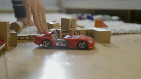 Tender hand playing with red car model on wooden blocks background Stock Footage 148438542