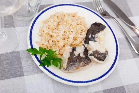 Tender meat of baked cod fillet is garnished with boiled basmati rice. Stock Photos