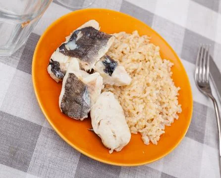Tender meat of baked cod fillet is garnished with boiled basmati rice. Stock Photos