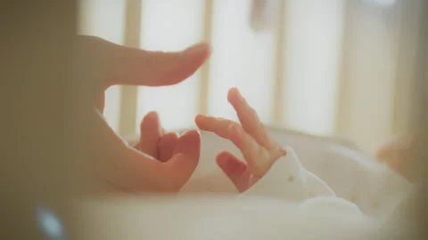 Tender moment shared between parent and baby in soft light near window Stock Footage 323927972