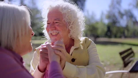Tender old couple holding hands sitting on a park bench Stock Footage 260577221