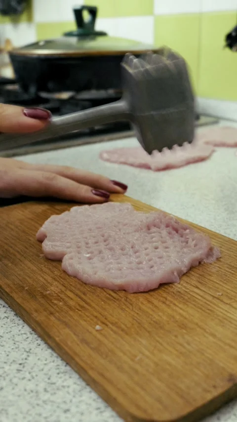 Tenderizing Raw Pork Cutlet with a Meat Hammer on a Wooden Board Stock Footage 324868034