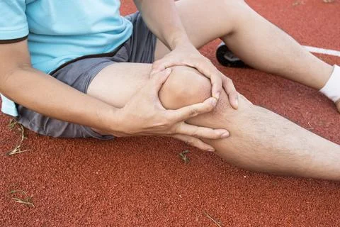 Tendon knee joint problems on Man leg from exercise In the stadium. Fotos de archivo