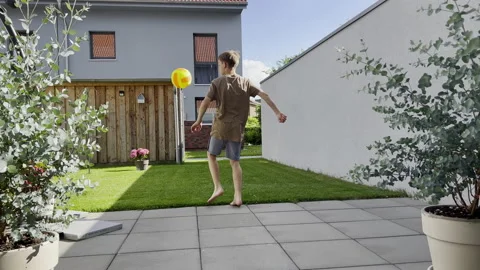 Tennager boy playing with ball at backyard during summer holidays Stock Footage 199505830