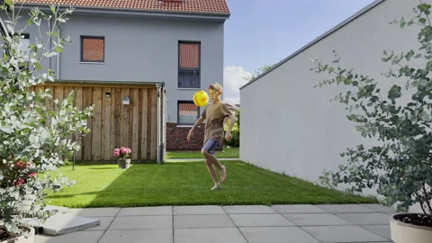 Tennager boy playing with ball at backyard during summer holidays Stock Footage 199508944